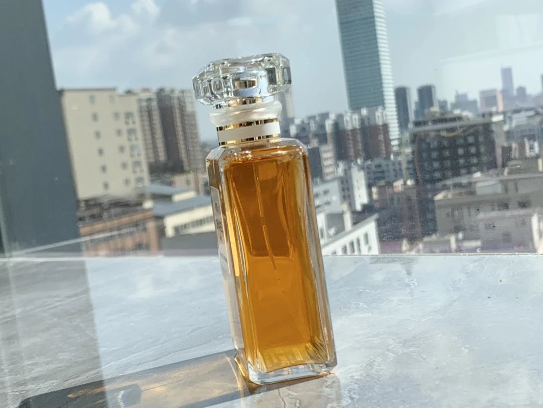 Perfume bottle on a rooftop with cityscape in the background