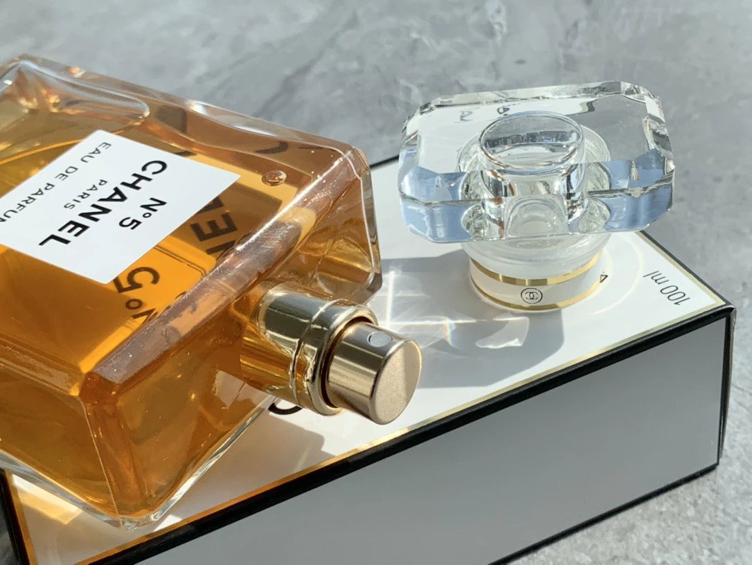 Chanel perfume bottle with gold cap on a reflective surface